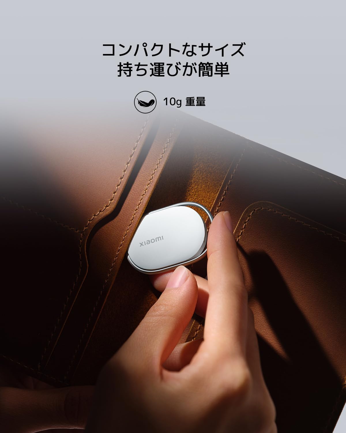 Xiaomi Smart Tag; Representative same-model-family image. One white Xiaomi Smart Tag attached to luggage; the original Japanese promotional wording is retained. The source listing sells four tags, but this single-tag model-family photograph does not establish the EMOS pack quantity. Luggage and accessories are illustrative; supplied quantity and finish confirmed on quotation.