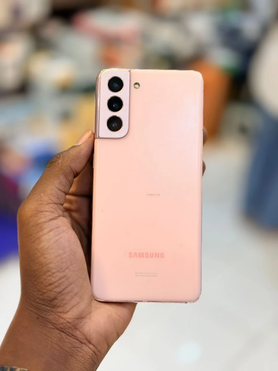 Samsung Galaxy S21 smartphone in a pink finish, rear view, held in the hand