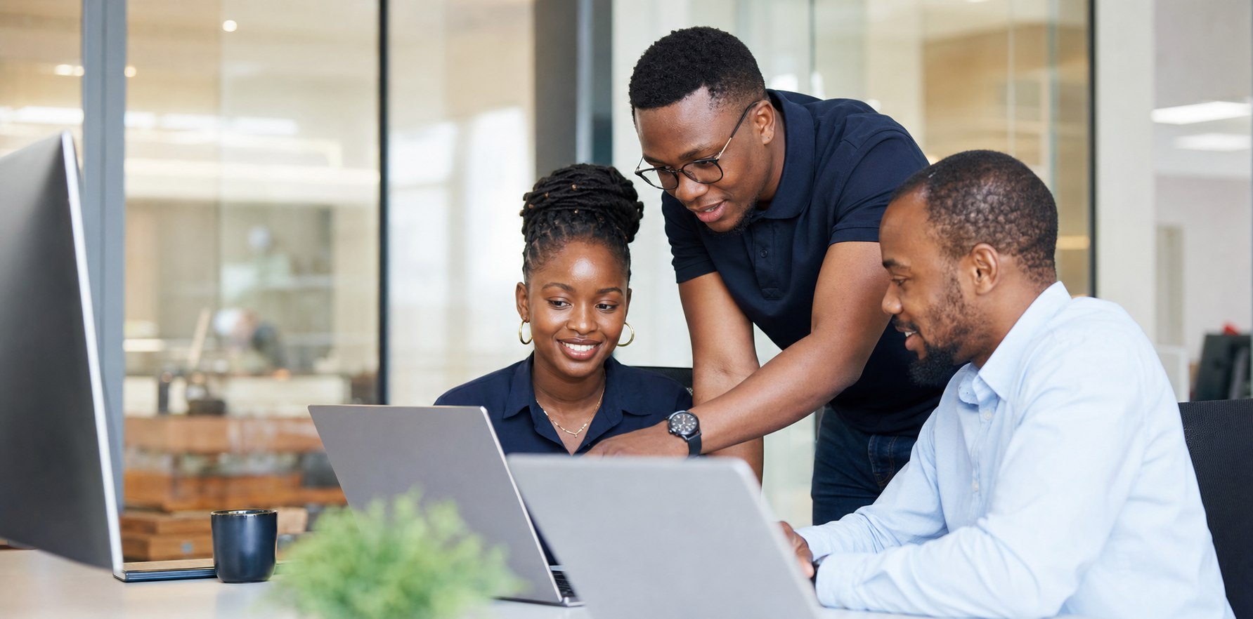 Emos IT professionals collaborating around laptops in a modern office